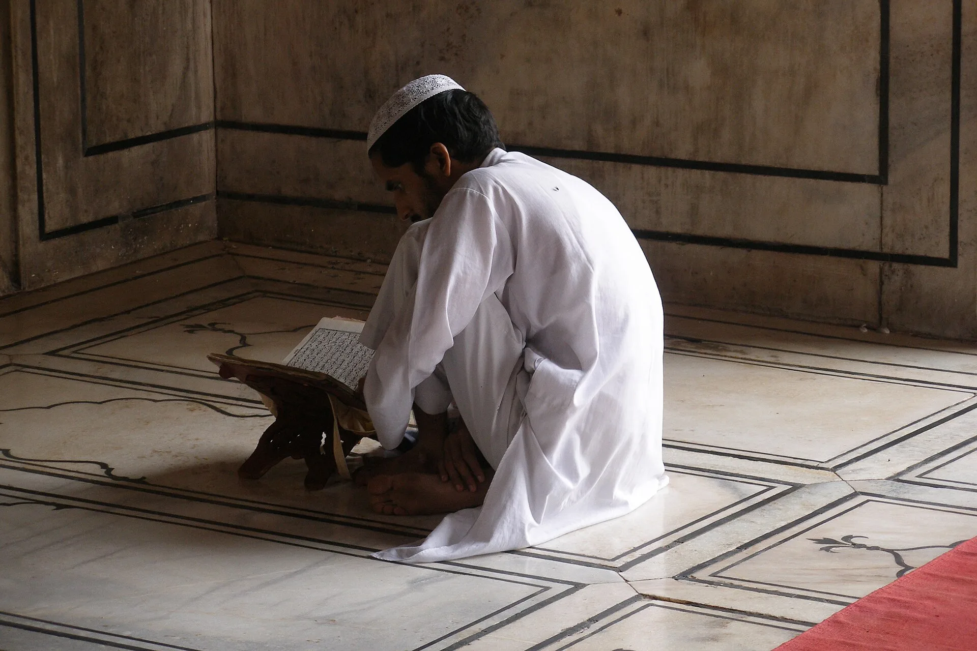 Fidèle en prière et en lecture du Coran sur un tapis