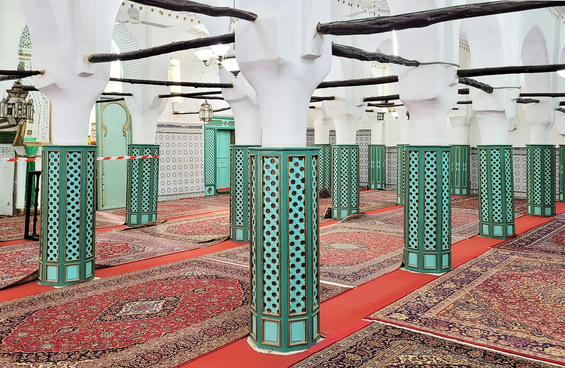 Salle de prière aux colonnes vertes et aux tapis rouges